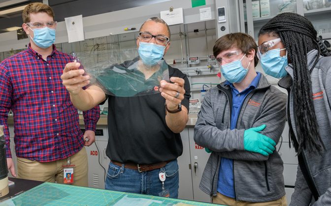 Gerry Brown (second from the left), an R&D Technical Fellow, holds a Chemours fuel cell membrane as fellow Blue Hens and Chemours R&D engineers Robbie Loesch (left), Joey Pritchard (second from right) and Brittany Georges (right) look on.