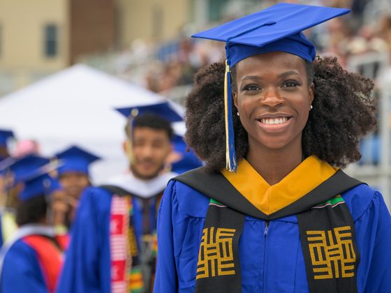 A student smiles in cap and gown