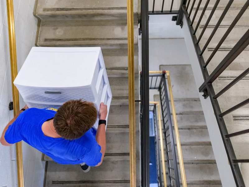 Student carries set of drawers in stairwell