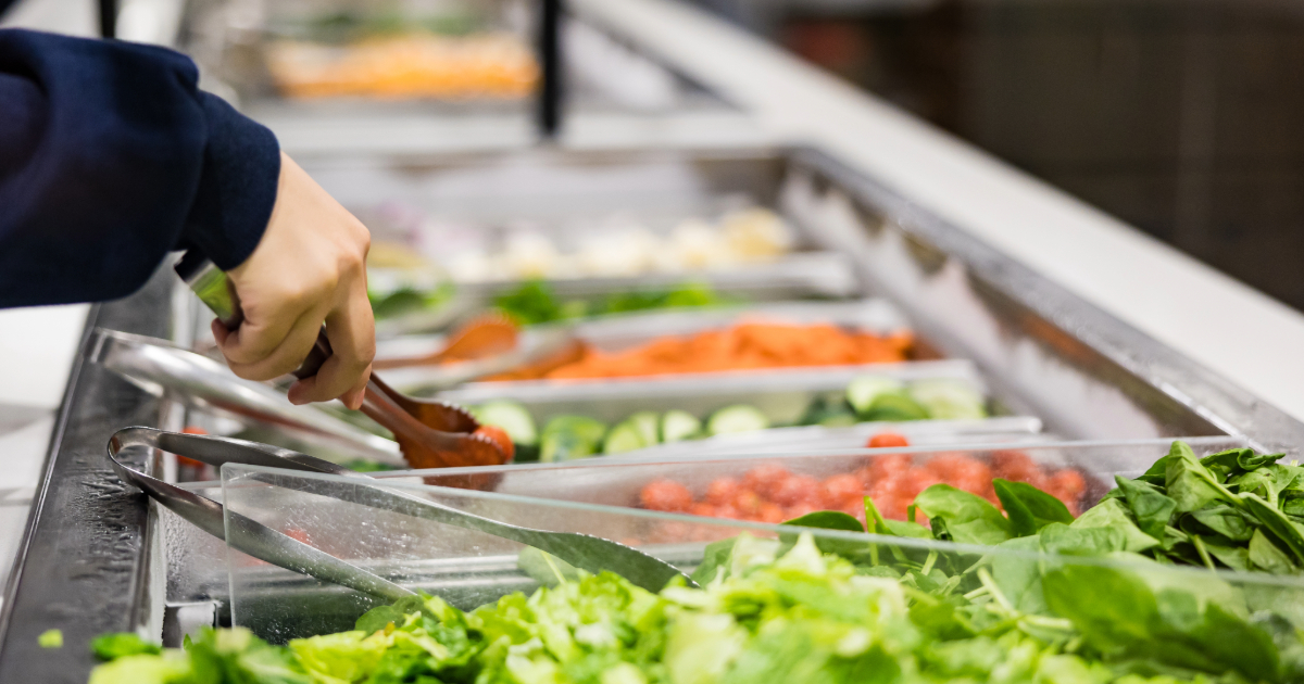 Hand with tongs at a salad bar