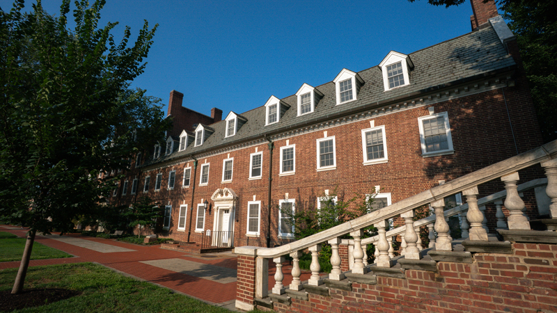 View of the front of Brown Residence Hall from the right, with a staircase to Main Street in the right part of the picture. There is also a brick walkway in front of the building. 
