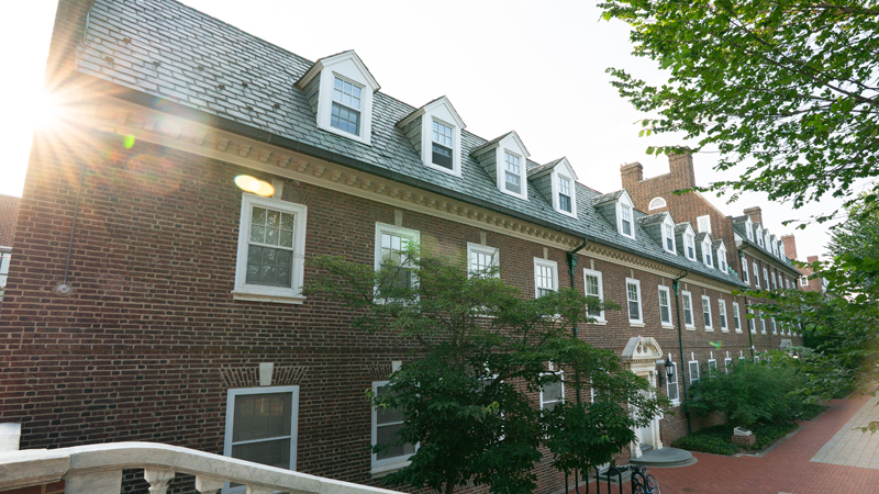 View of the front of Harter Residence Hall from on top of a staircase. The building is on the left and a brick walkway extends from the end of the staircase along the front of the building.