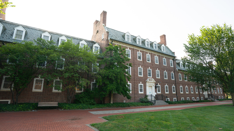 Outside view of main entrance to building from the right with five steps up to the main door and a brick walkway along the front of the building.