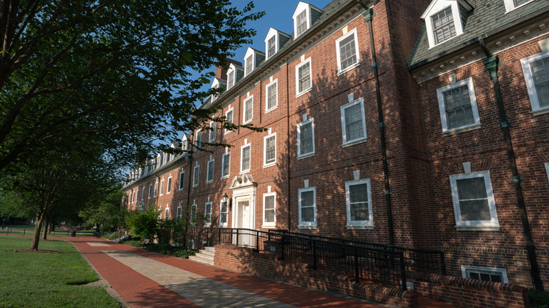 Angled view of front of Sypherd Residence hall with trees on grass on the left side of the picture and front part of the building on the right side.