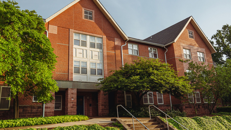 Steps leading up to the entrance of Ray Street B, with greenery and trees around the front of the building. The steps connect to a concrete walkway that follows along the front of the building.