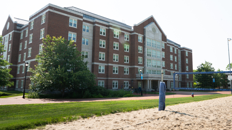 View of the front entrance of Louis Redding Residence Hall, with part of the beach volleyball sand courts in the front part of the picture.