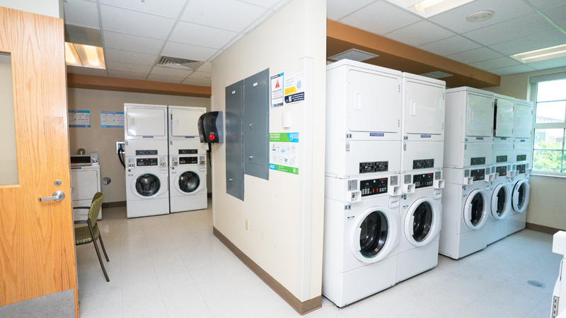 Room split into two sections with stacked washer and dryer units in each section. 