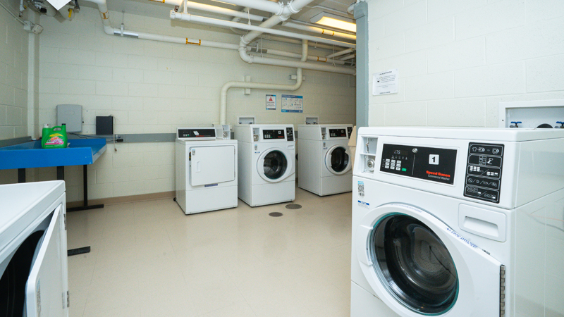 Multiple washer and dryer units around the space, with a folding table in the back left corner.