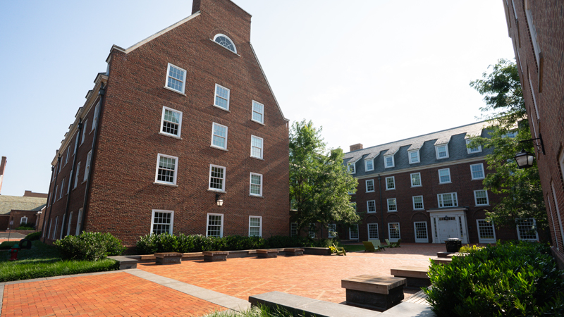 Outside view of back entrance of South Academy Residence hall with courtyard space and different seating options available. 