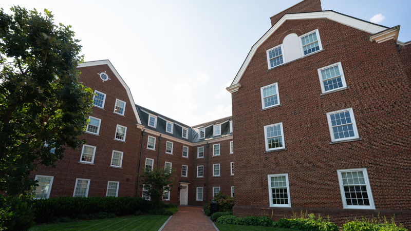 Outside view of back entrance of South Academy Residence hall with courtyard space and different seating options available. 