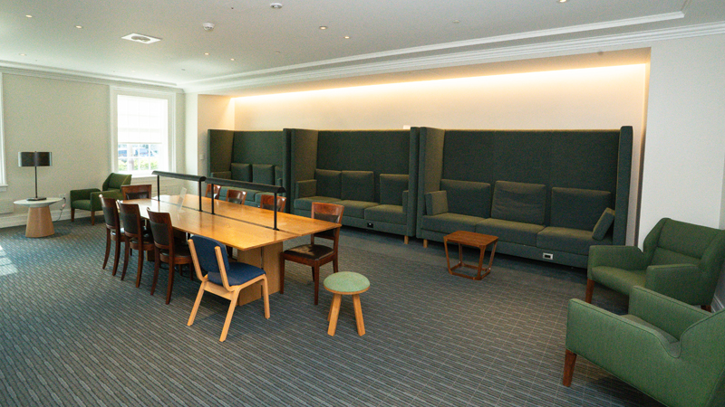 Couches along the back wall with a table and chairs in the middle of the room. There are lounge chairs against the walls on either side of the table. 