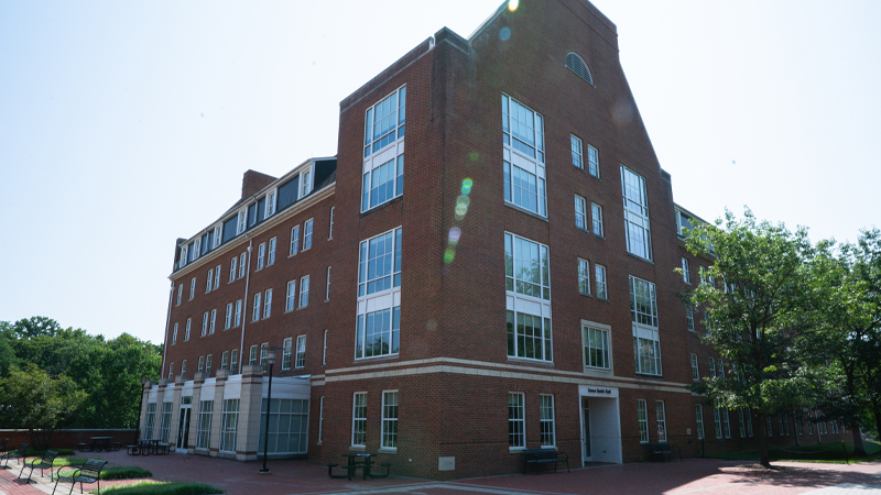 James Smith Residence hall with a brick walkway, and benches and tables to sit in a courtyard area.