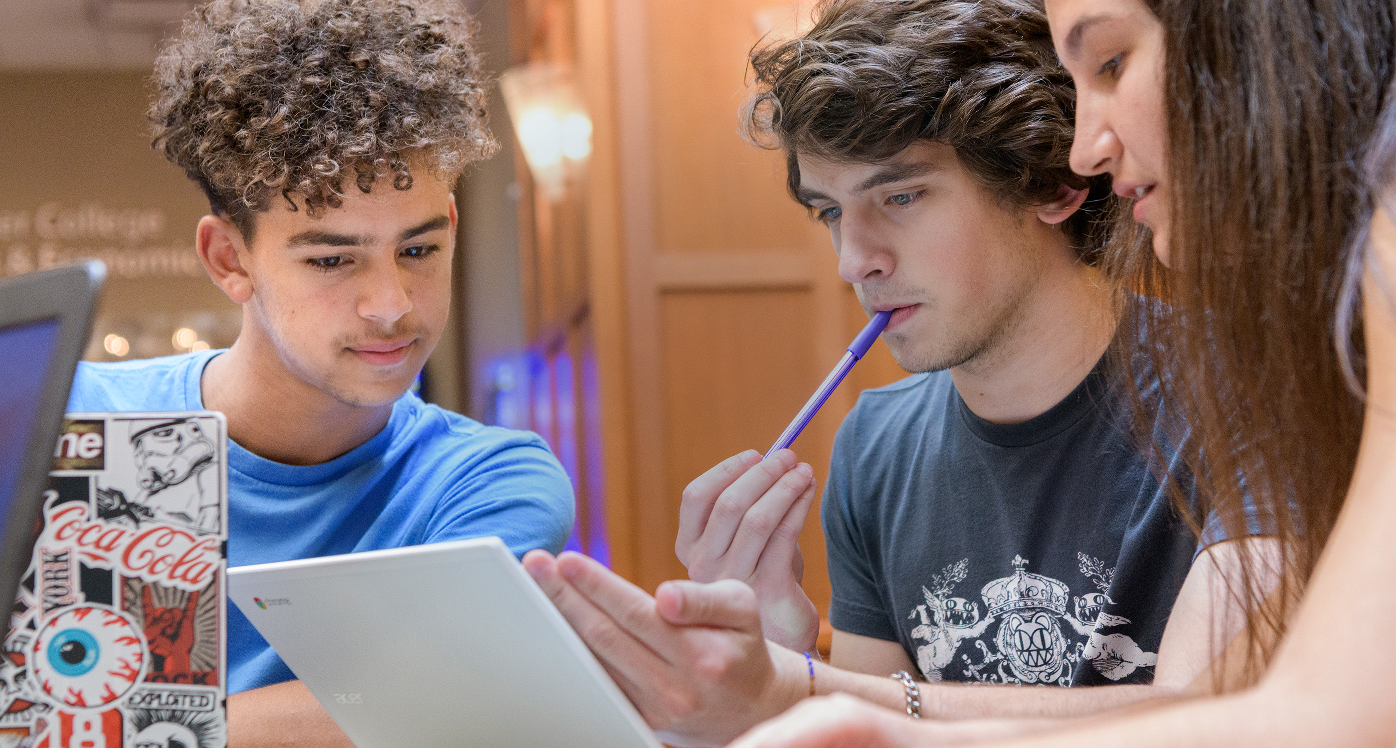 A group of students discussing something over a computer.