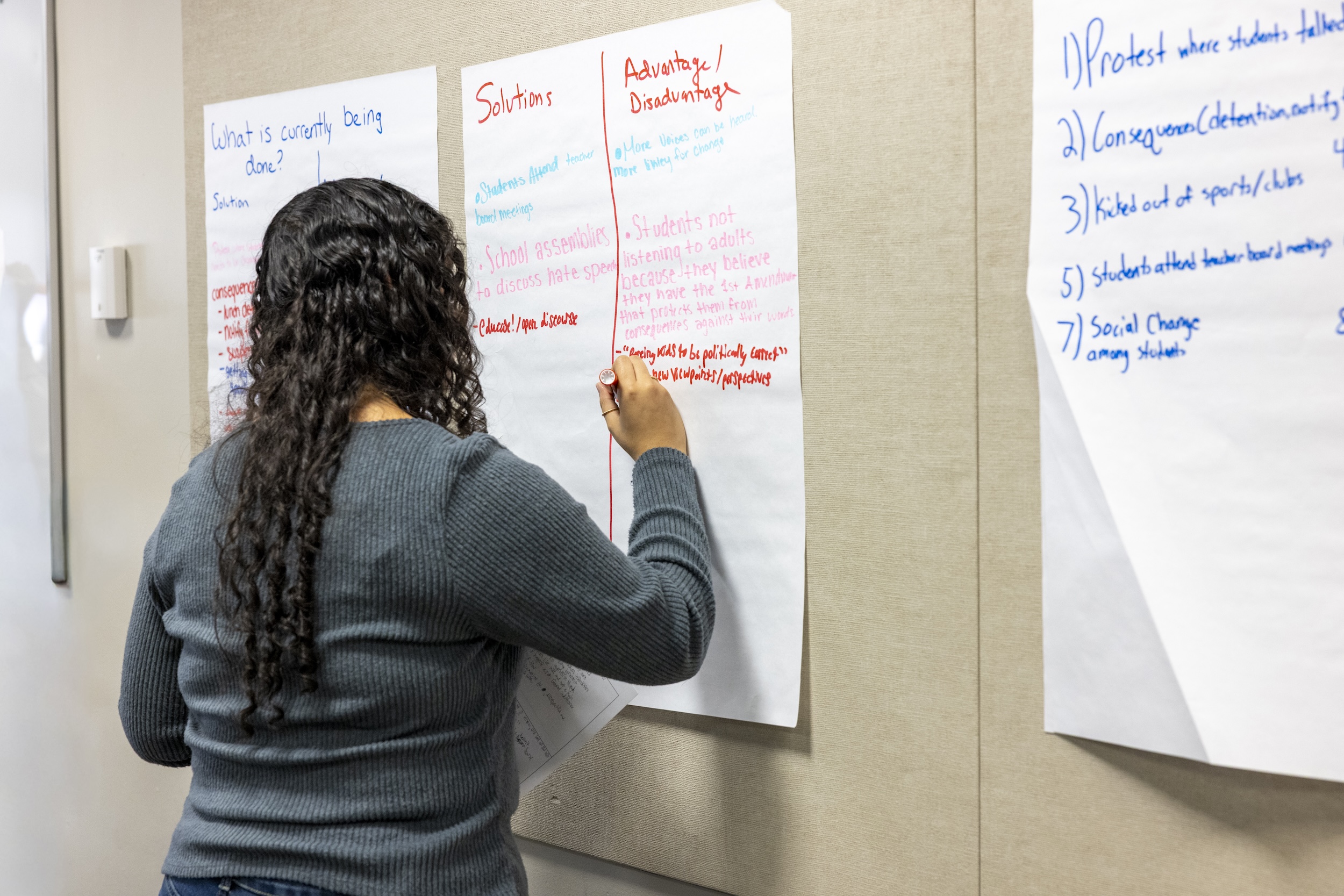 Student writing on a poster at DE Dialogues
