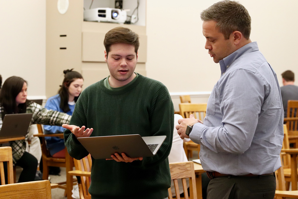 Brandon McFadden speaks with a student holding a laptop