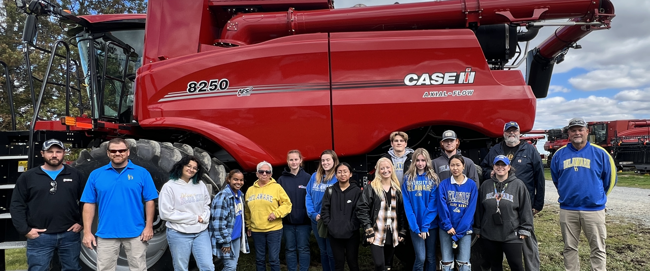 AGRI 130 students pose in front of a CASE combine