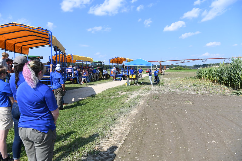 Three blue and gold wagons line up to listen to presenters 