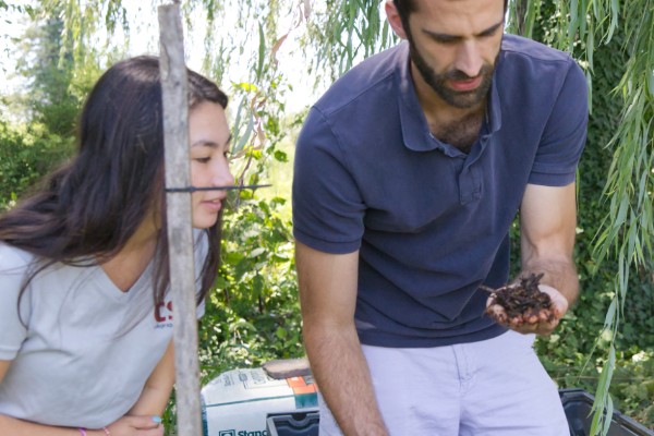 Michael Crossley shows a handful of lesser mealworm in a pile of poultry litter to a University of Delaware student