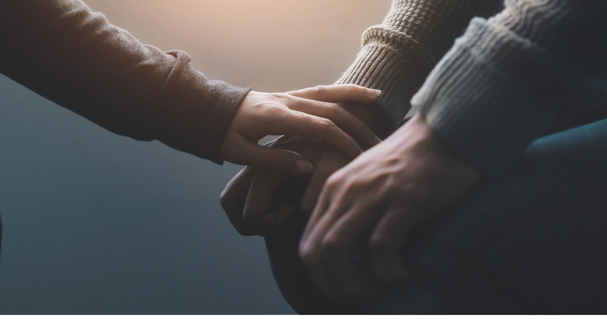 Someone comforting another person by laying their hand on theirs. 