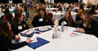 A group of young women sitting around a table at a conference