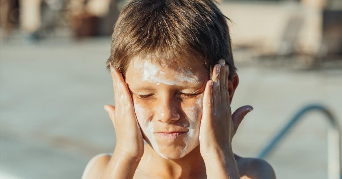 Boy putting on sunscreen