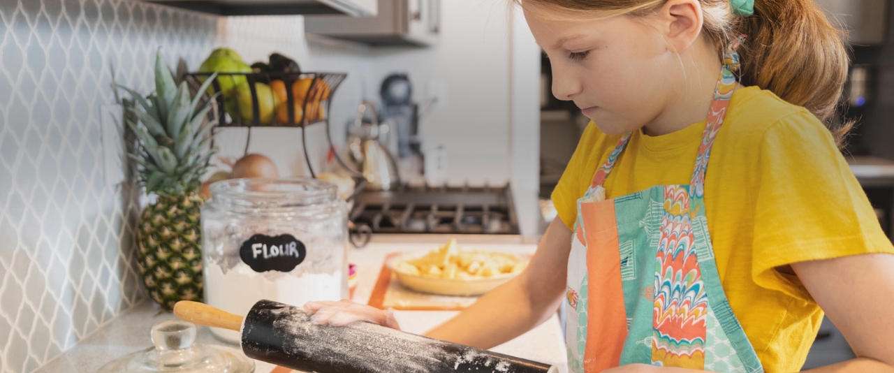 A girl learning to roll out dough