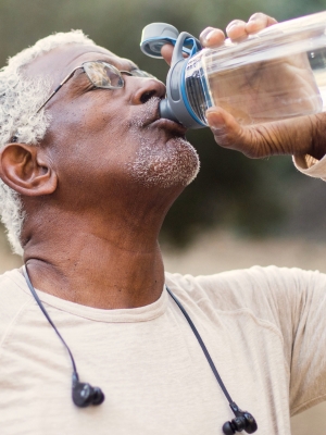 Man drinking from a water bottle while working outside.