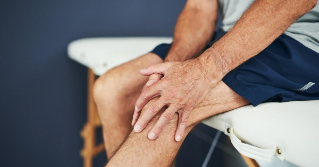 Someone sitting while holding their knee in pain