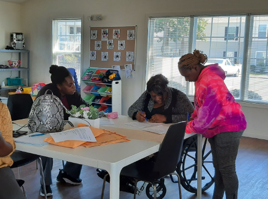 Adults filling out some forms in a classroom setting.