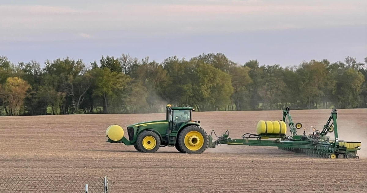 A tractor in a field planting corn