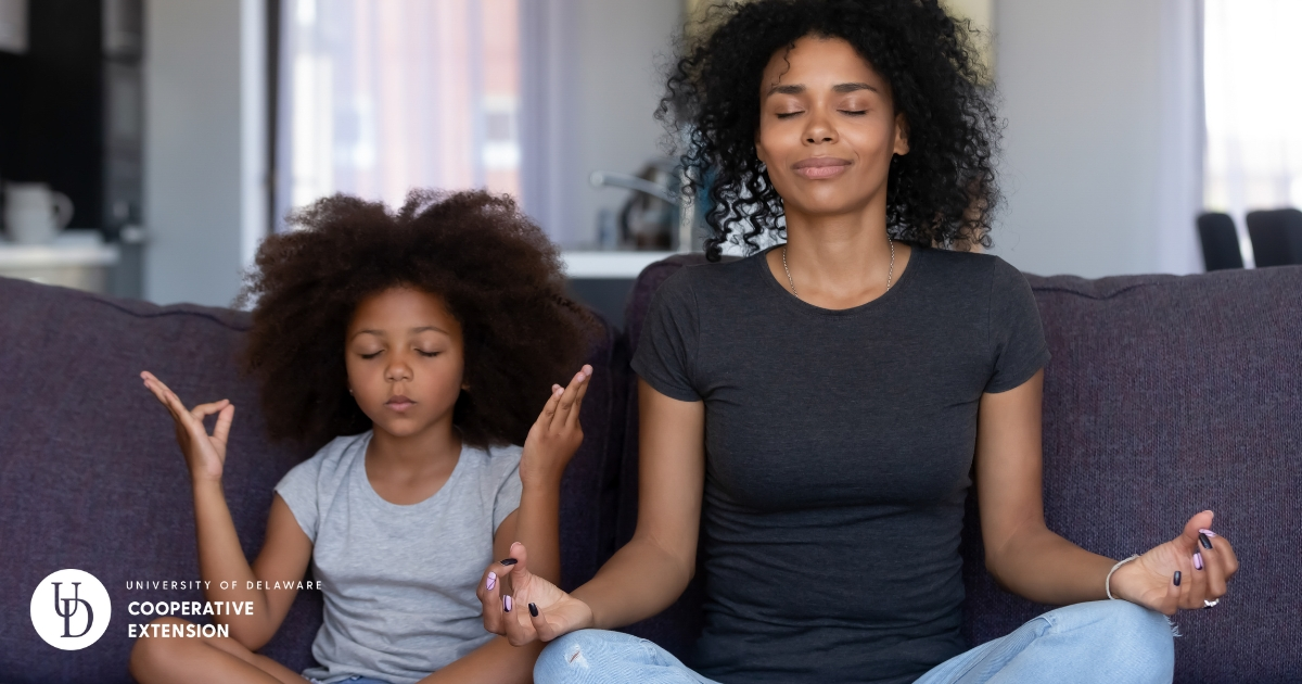 A mom meditating on the couch with her daughter