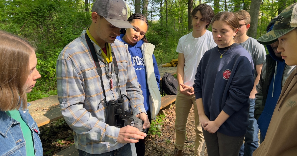 Students gather around to examine a bird caught using a mist net.
