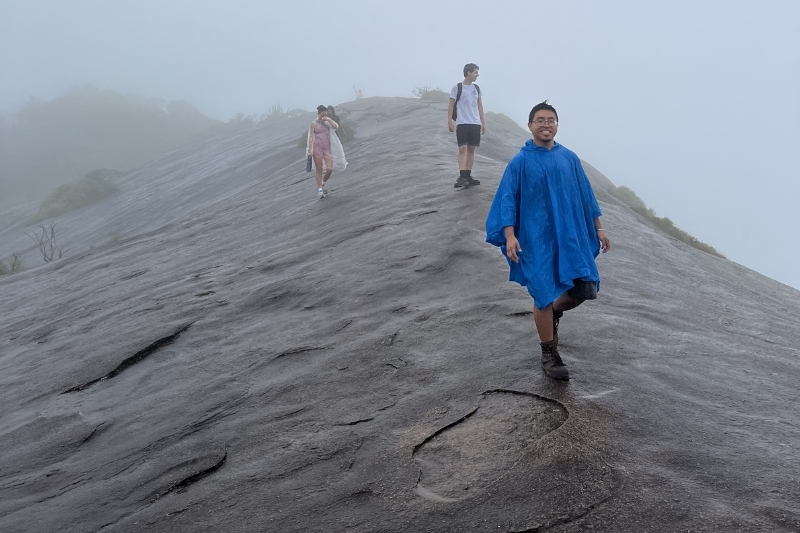 Students stand at the top of a mountain on a cloudy day.
