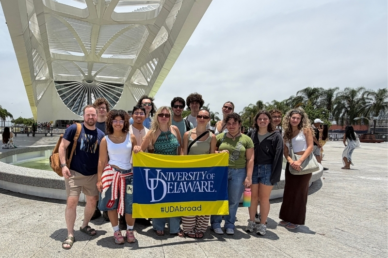 UD students hold a UD flag outside of the Museum of Tomorrow.