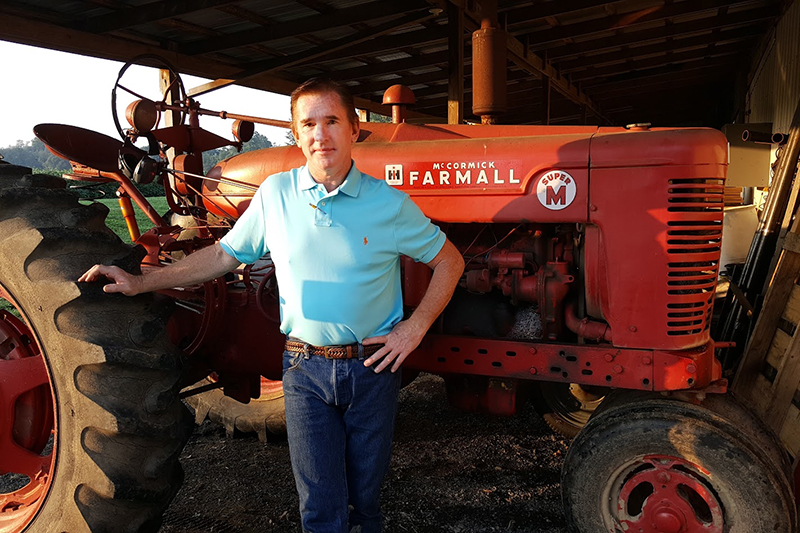 A young James Glancey poses in front of a tractor.