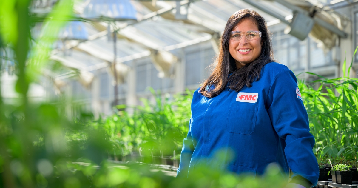 Tiffany Carro stands among plants in a greenhouse.