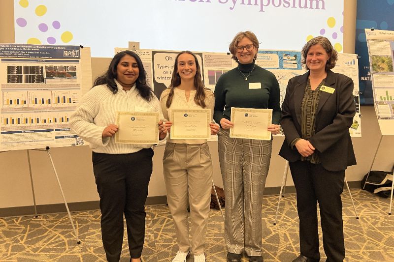 Graduate student award winners stand next to Tanya Gressley, holding their award certificates.