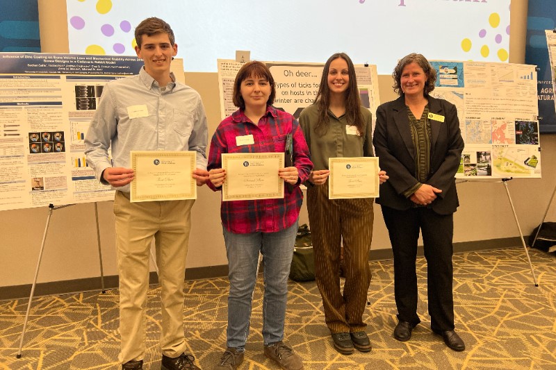 Undergraduate award winners stand next to Tanya Gressley, holding their award certificates.