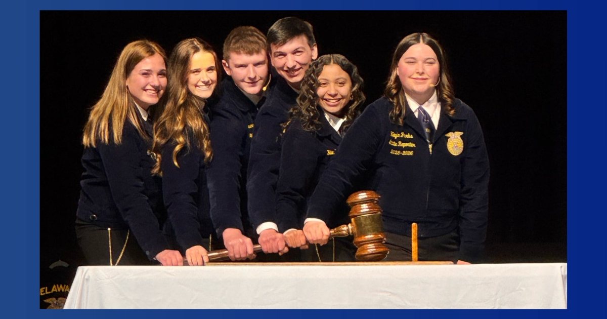 Six Delaware FFA state officers hold a gavel together on top of a table.