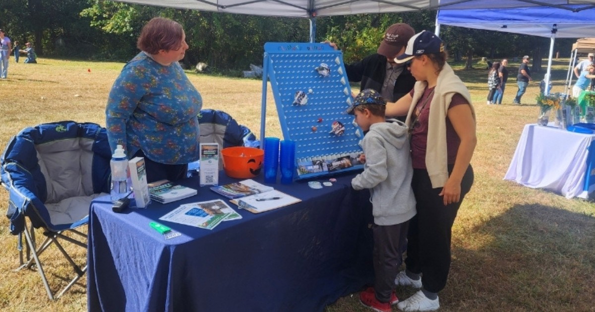 Lee Aiken, DNREC climate policy planner and UD Class of 2018 alumna, helps a family to learn more about climate risks while playing 