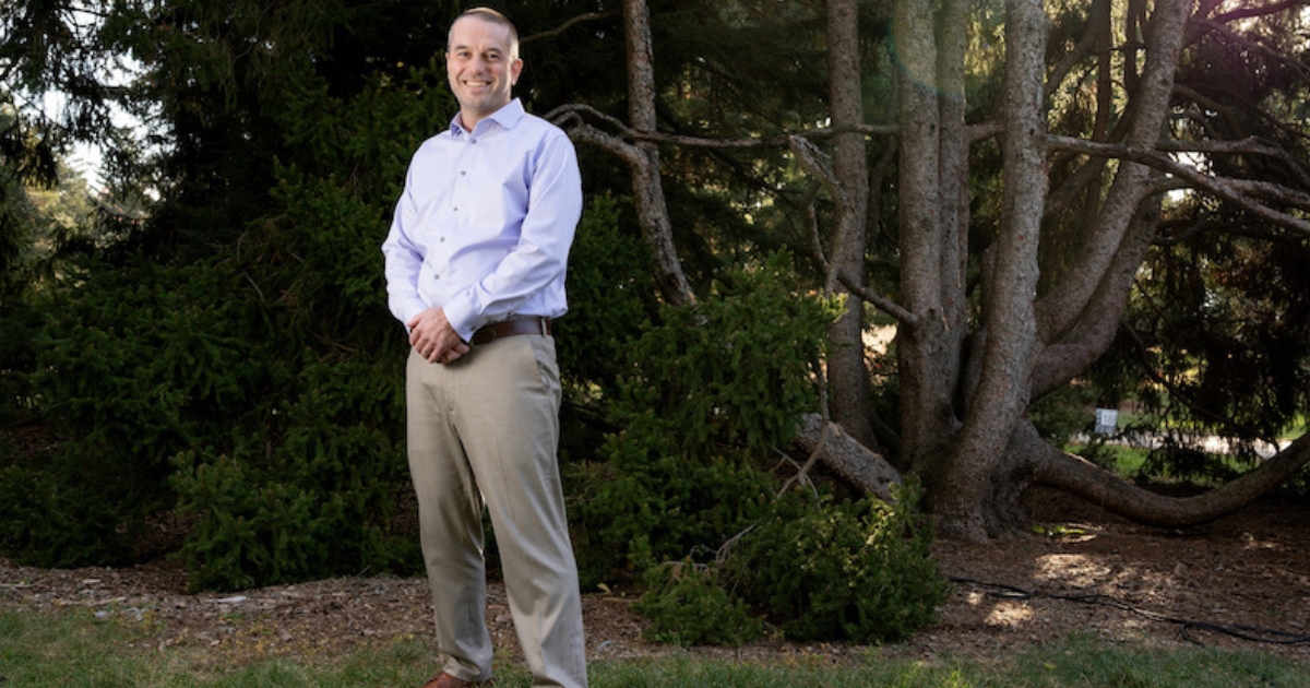 Mark Richardson poses for a photo standing in front of trees.