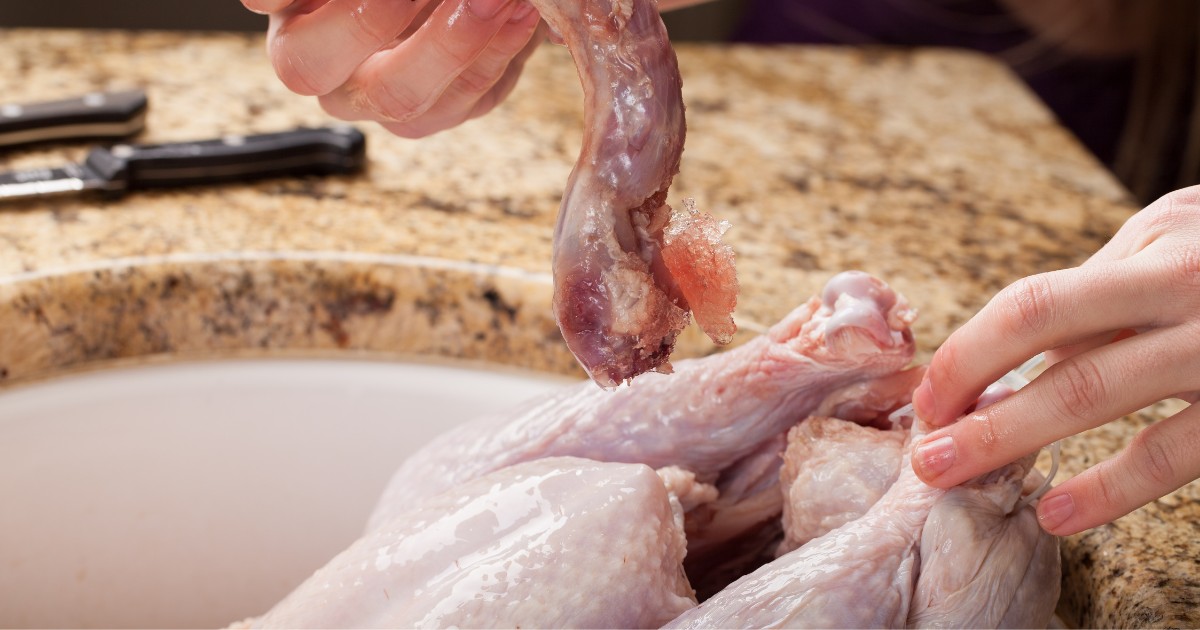 A cook washing turkey in the sink