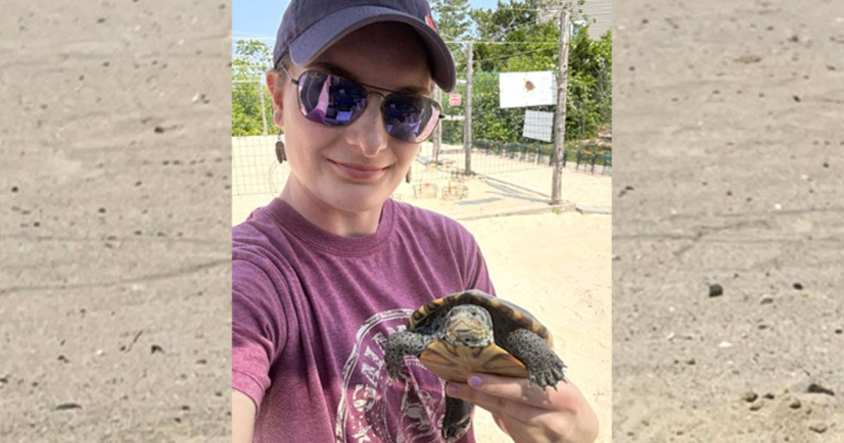 Samantha Melanson holds up a turtle to the camera.