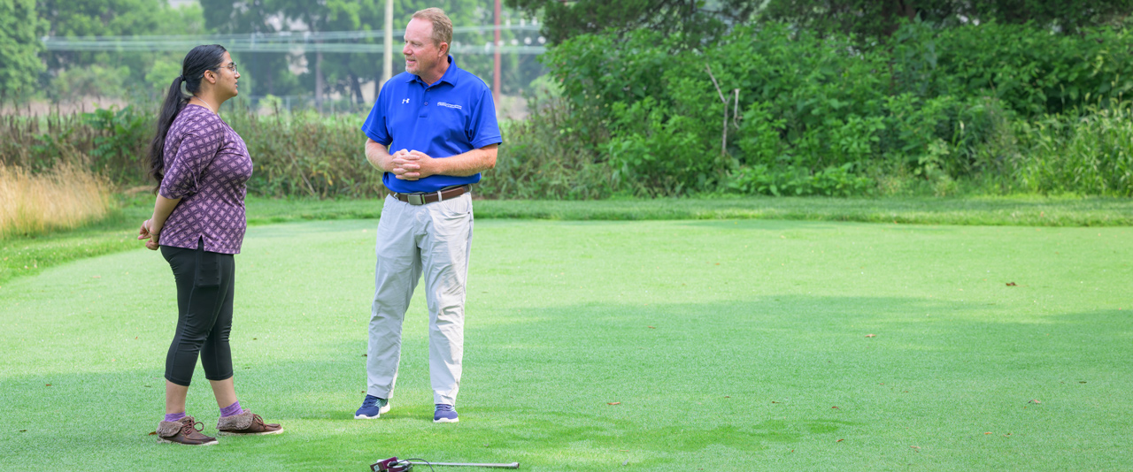 Charanpreet Kaur (left) and Erik Ervin (right) stand on a turf research plot at the University of Delaware College of Agriculture and Natural Resources. 