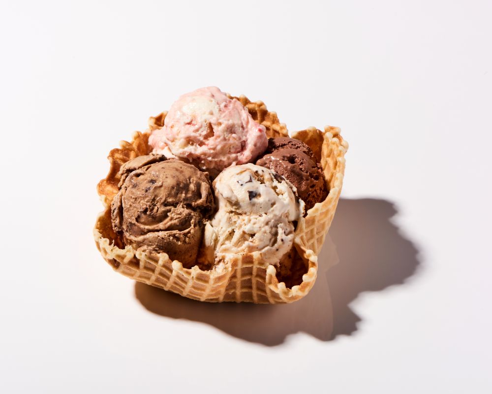 Three scoops of UDairy Creamery Ice Cream in a waffle cone bowl
