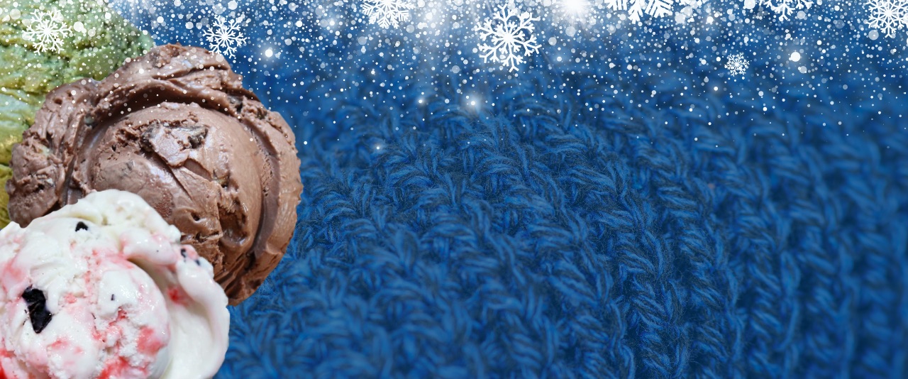 Scoops of three ice cream flavors against a backdrop of blue sweater material and snow.
