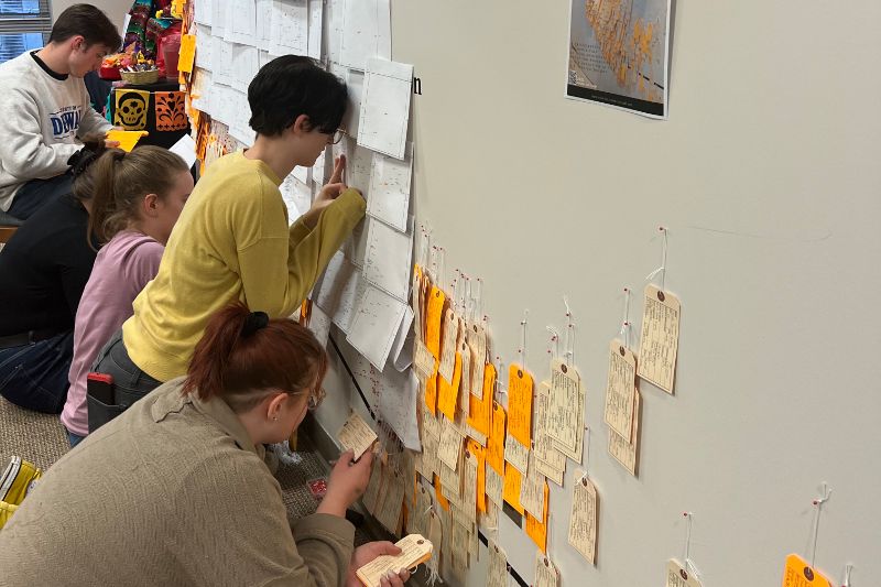 Anthropology students install a wall of post-it notes about immigration