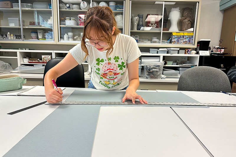 Miranda Harman (x’29) measures archival BlueBoard © to create a custom box in Madeline Hagerman’s honors course in the fall of 2025 (Image by Madeline Hagerman).