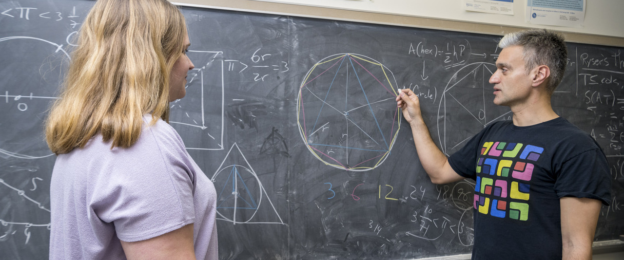 A photo of students completing a math equation on a blackboard