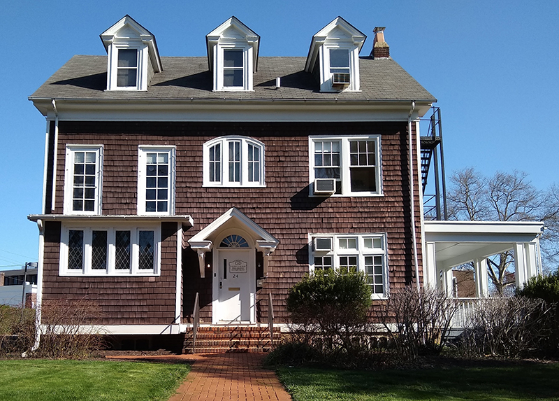A brown colonial house with windows and three dormers.